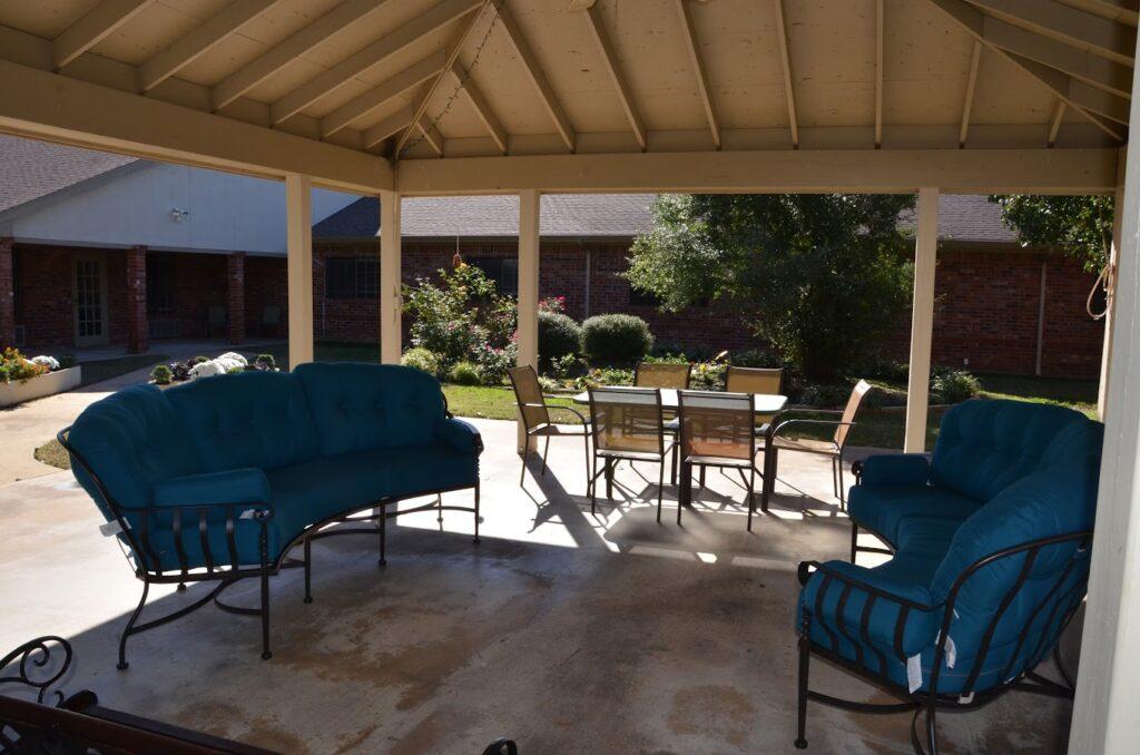 Covered patio with blue chairs and tables, ideal for relaxing and gatherings in Denison, TX