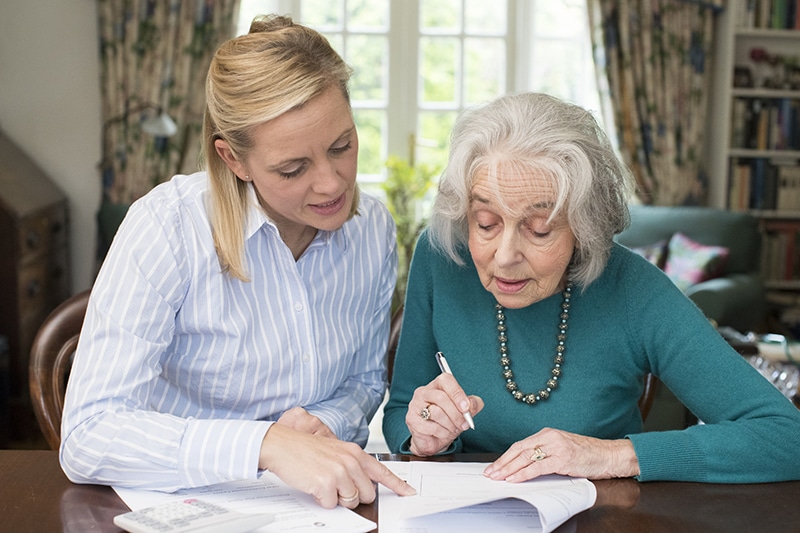Woman reviewing documents at a table with her elderly mother